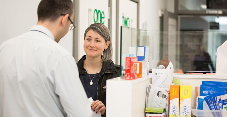 Woman picking up prescription from pharmacist.