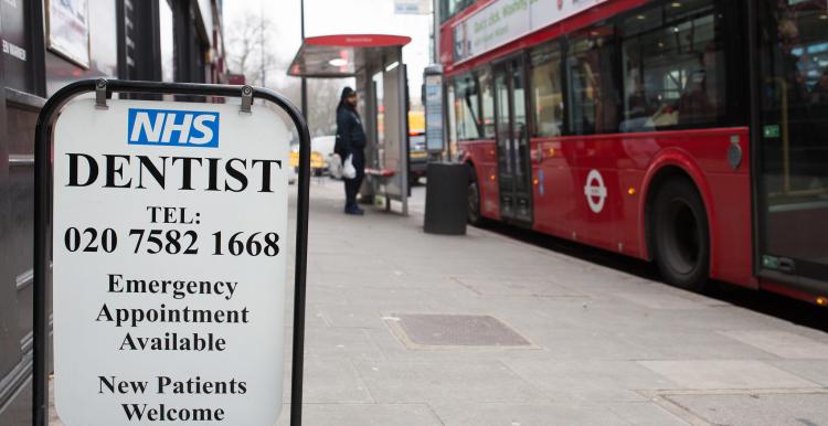 High street NHS dentist sign with bus in the background.