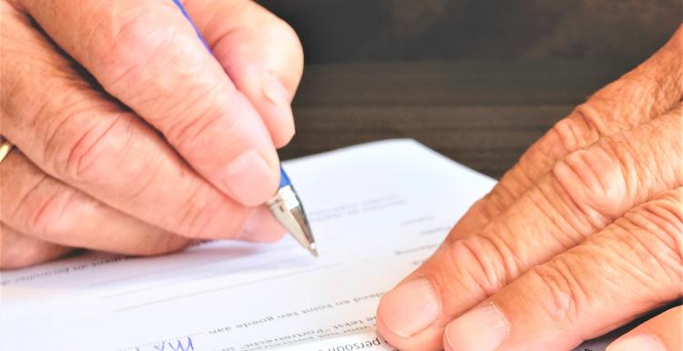 an old hand scribbling something with a pen onto a paper