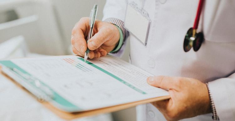 a doctor is holding a form and filling it out 