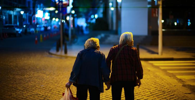 Elderly person sitting on a bench with a friend.