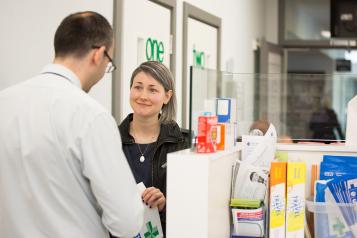 Woman picking up prescription from pharmacist.