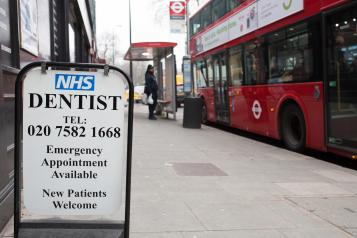 High street NHS dentist sign with bus in the background.