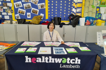 Woman smiling behind a Healthwatch table