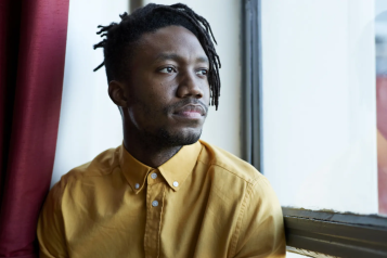 Serious black man looking out a window