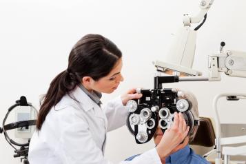 Optician administering an eye test to a man sitting down