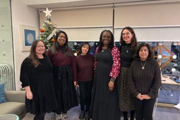 Six women standing in front of a Christmas Tree