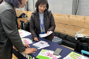 Two women talking next to a Healthwatch Lambeth table