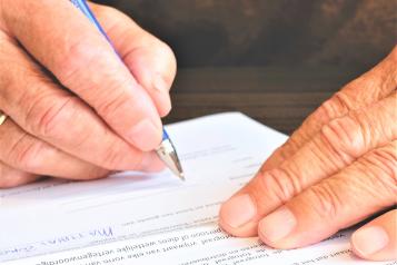 an old hand scribbling something with a pen onto a paper