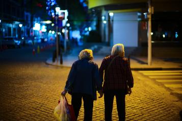 Elderly person sitting on a bench with a friend.