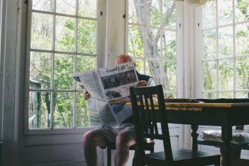 an older man reading by the window