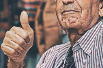 an old man with his thumbs up 