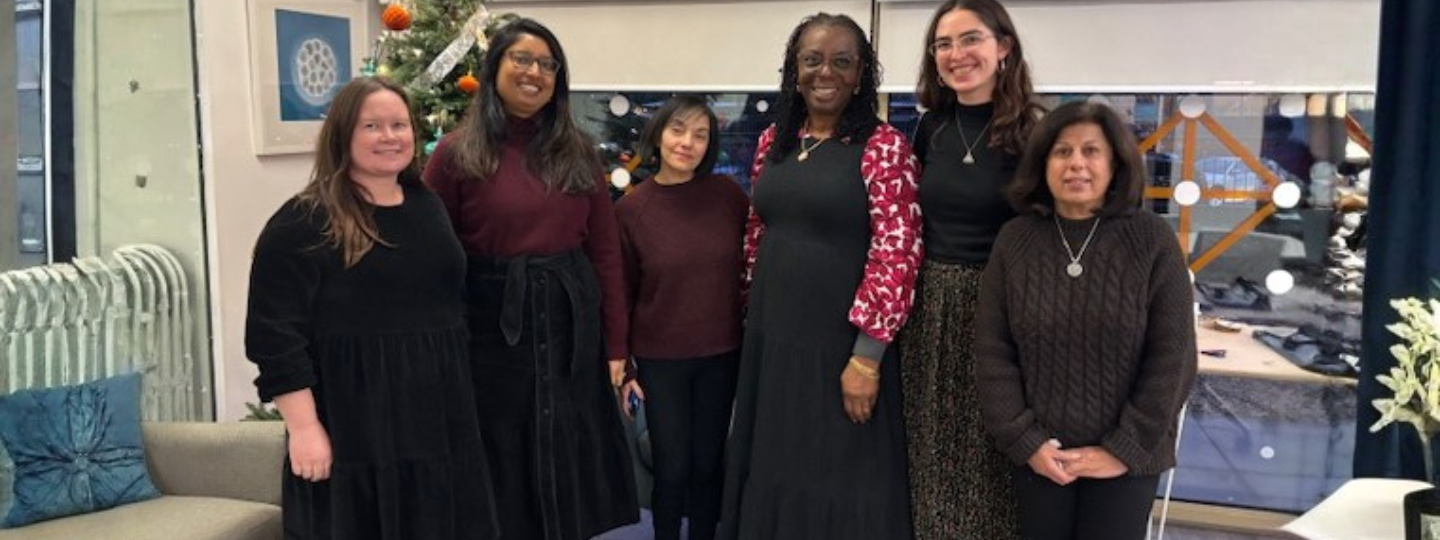 Six women standing in front of a Christmas Tree smiling
