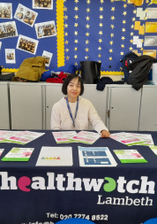 Woman smiling behind a Healthwatch table