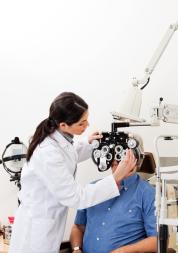 Optician administering an eye test to a man sitting down