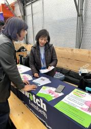 Two women talking next to a Healthwatch Lambeth table
