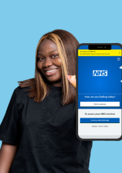 Woman smiling holding a phone towards the camera. On her screen is the NHS App log-in screen.
